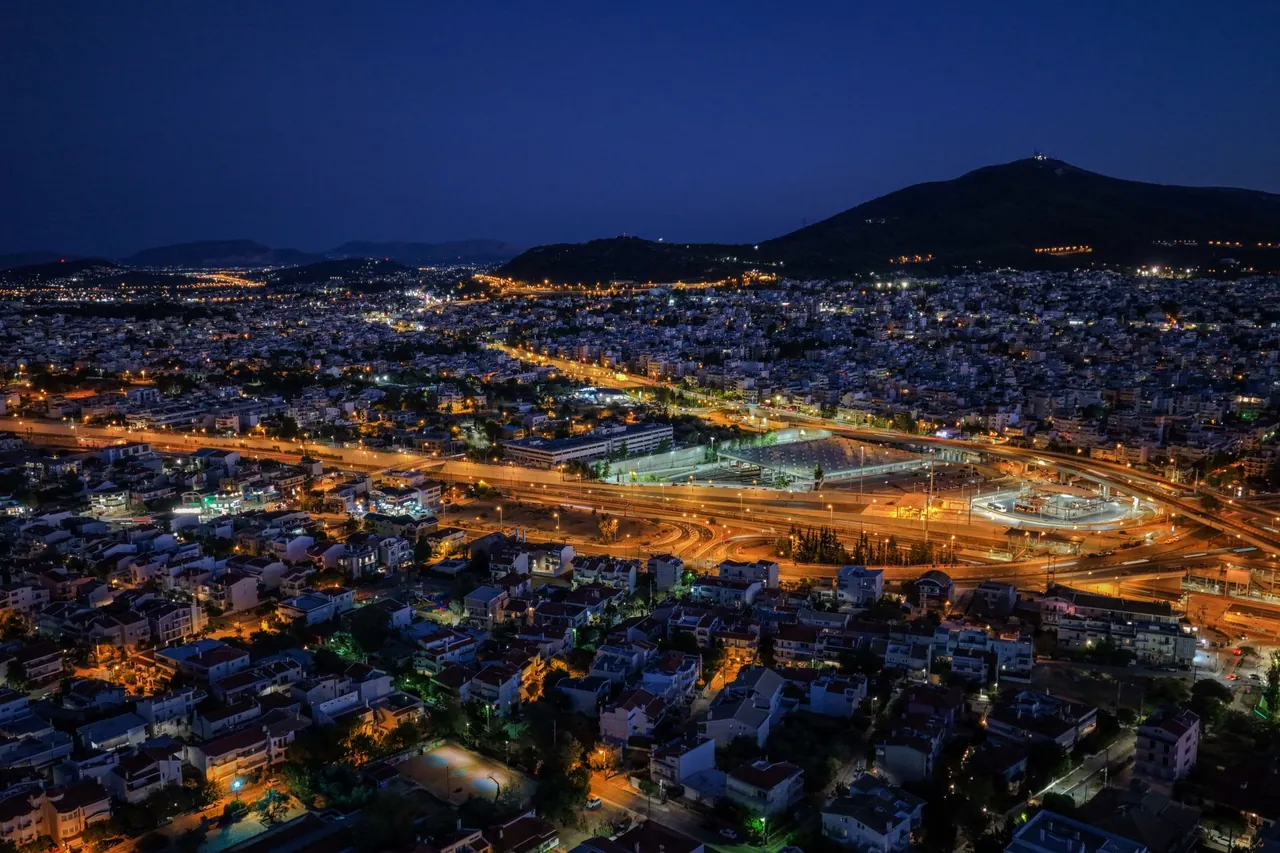 An Athens suburb lit up at night, with a busy road and illuminated buildings