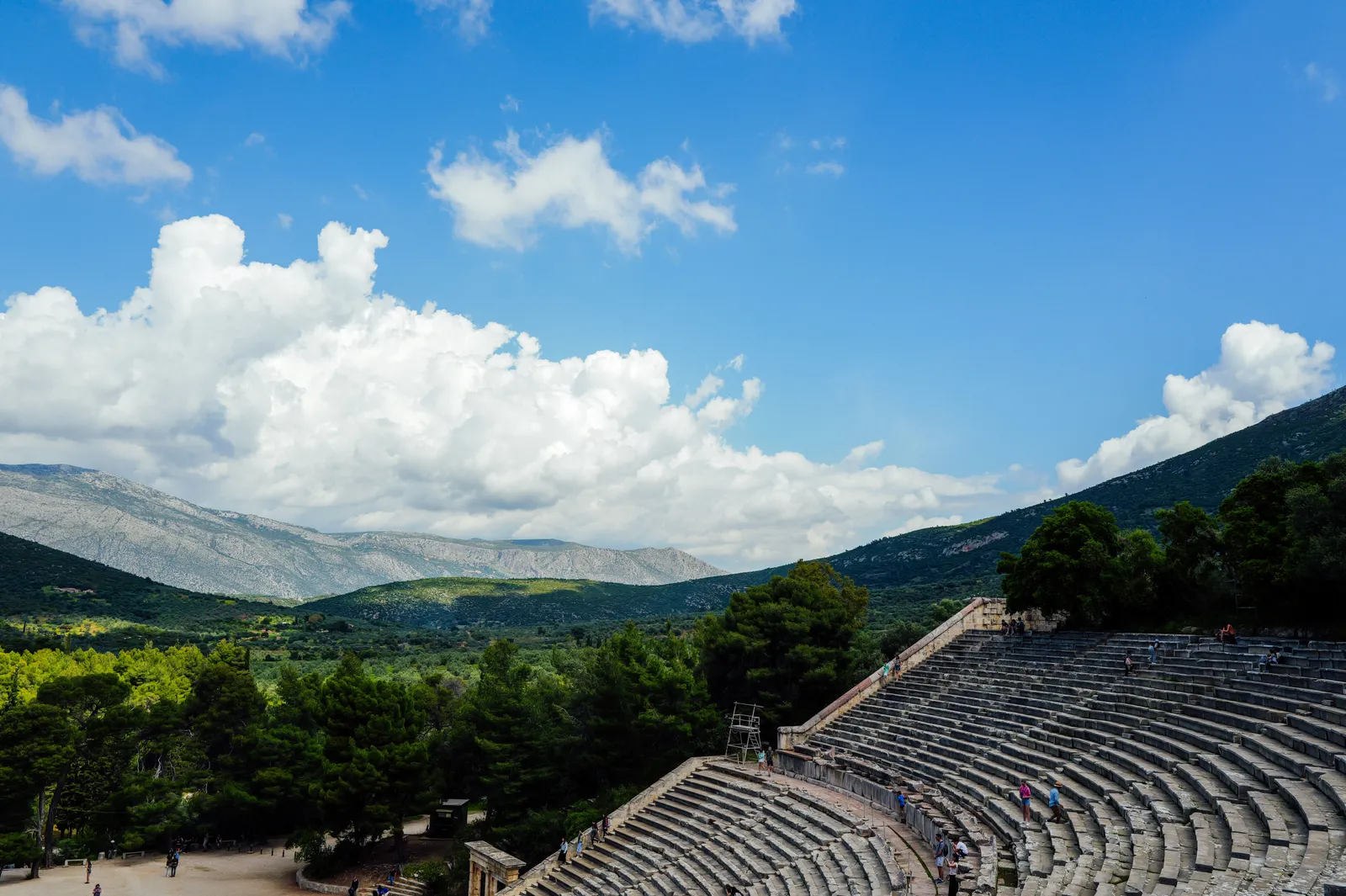The upper stone tiers of the ancient theatre of Epidaurus with the green hills of the Peloponnese behind, Greece