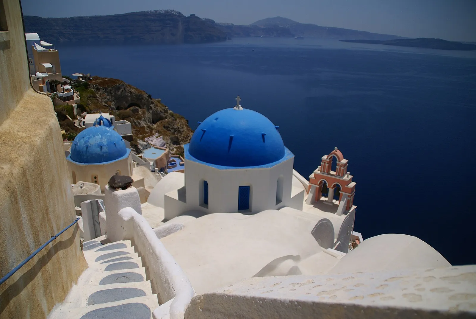 Blue domed churches of Oia village above the caldera on Santorini island, Greece, in bright daylight