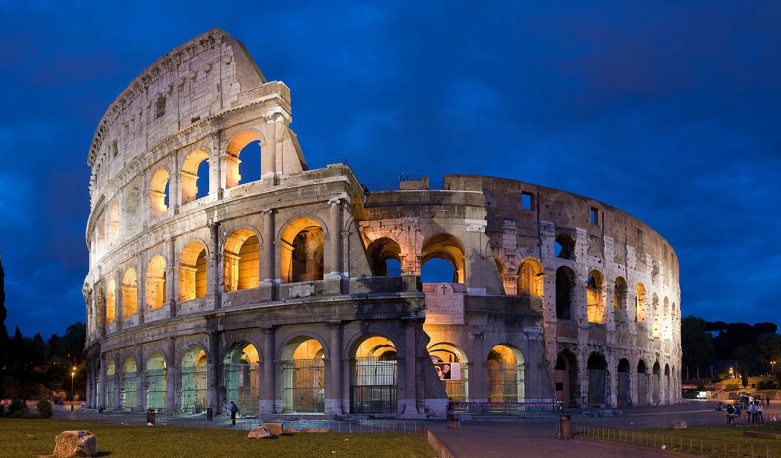 The Colosseum in Rome, Italy, under a bright sky with tourists walking around its ancient arches