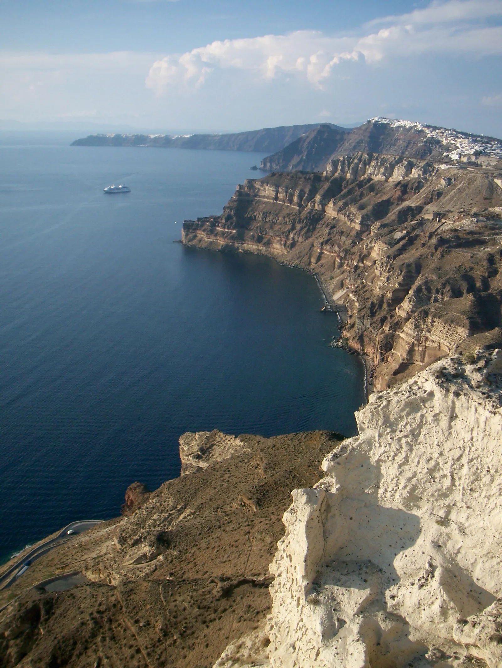 Whitewashed houses stacked on the steep caldera cliffs of Santorini, Greece, under a clear blue sky