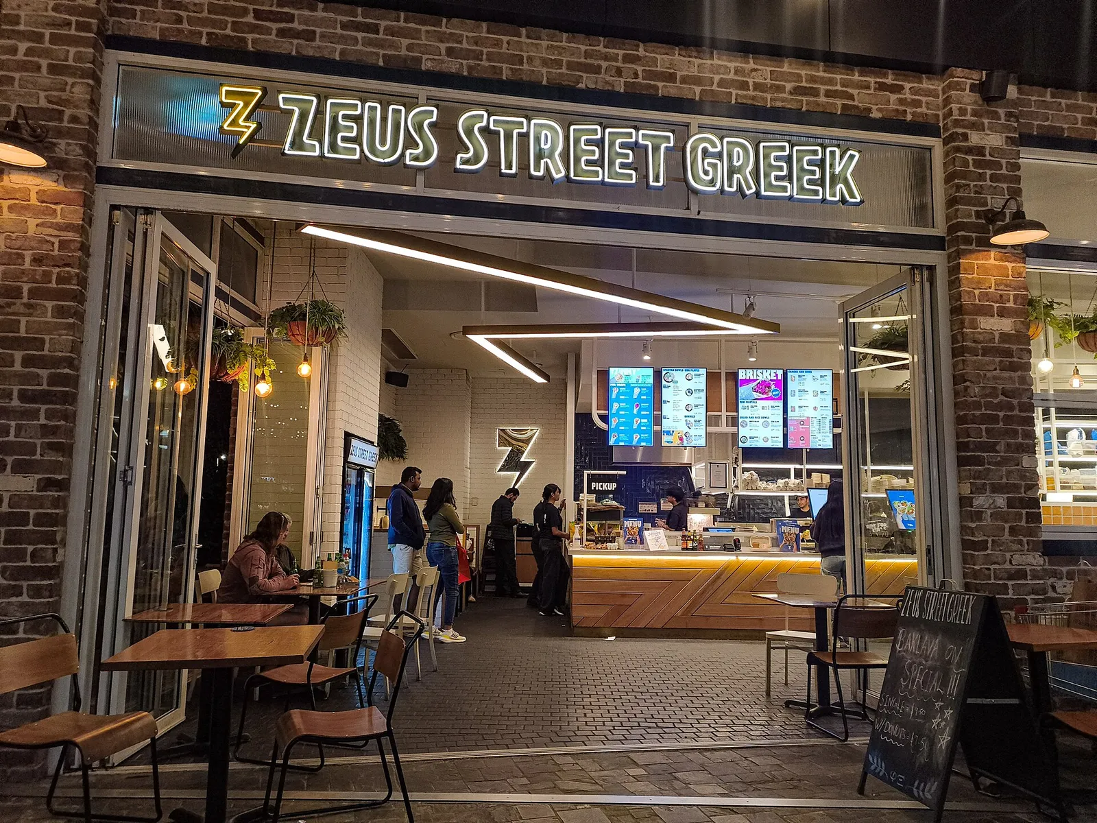 צלחת לוקומדס כדורי בצק מטוגנים מוזהבים בדבש וקינמון בדוכן רחוב מתוק ביוון