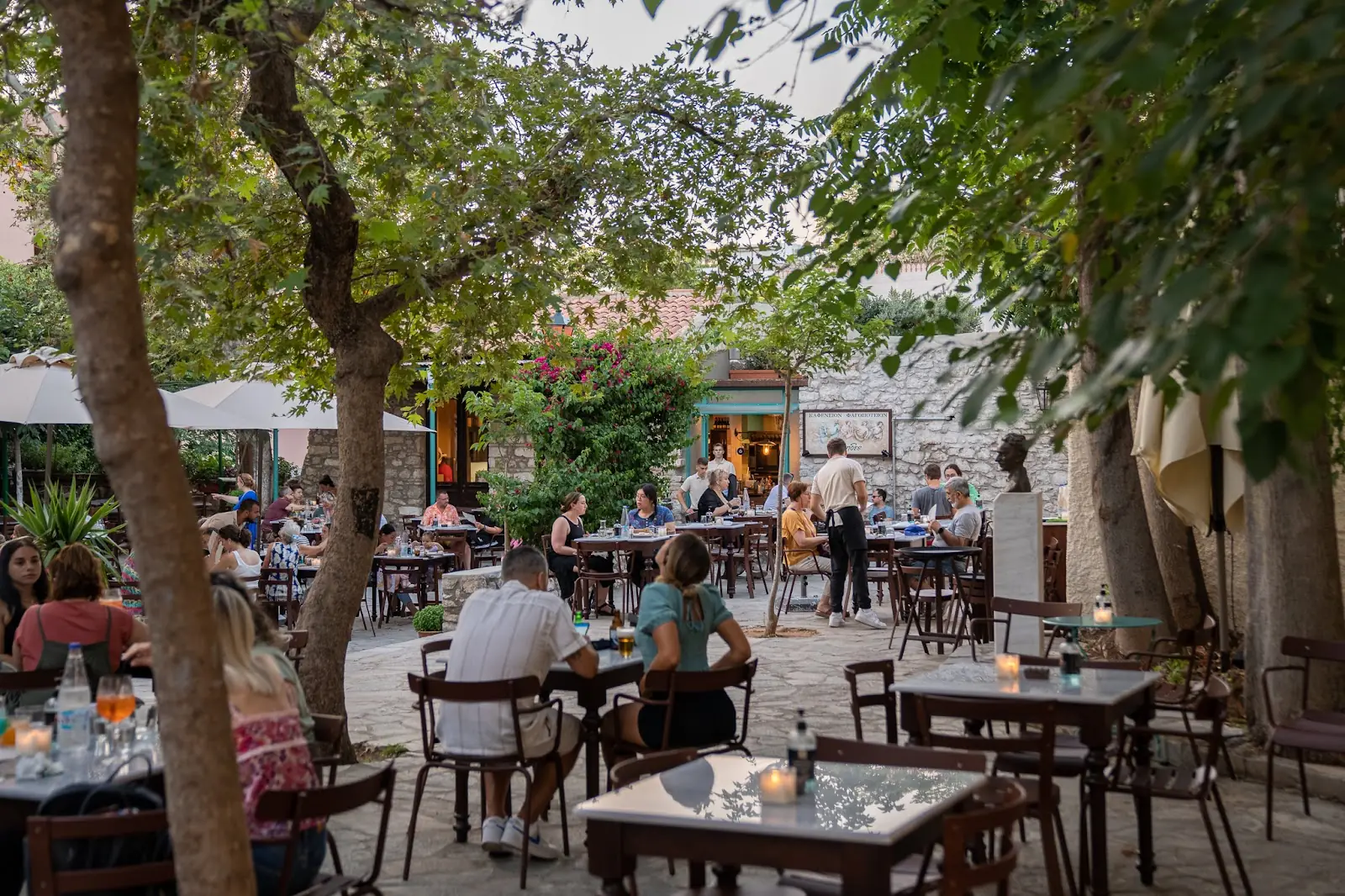 Outdoor taverna tables in Plaka, Athens, Greece, set for a meal with the Acropolis nearby