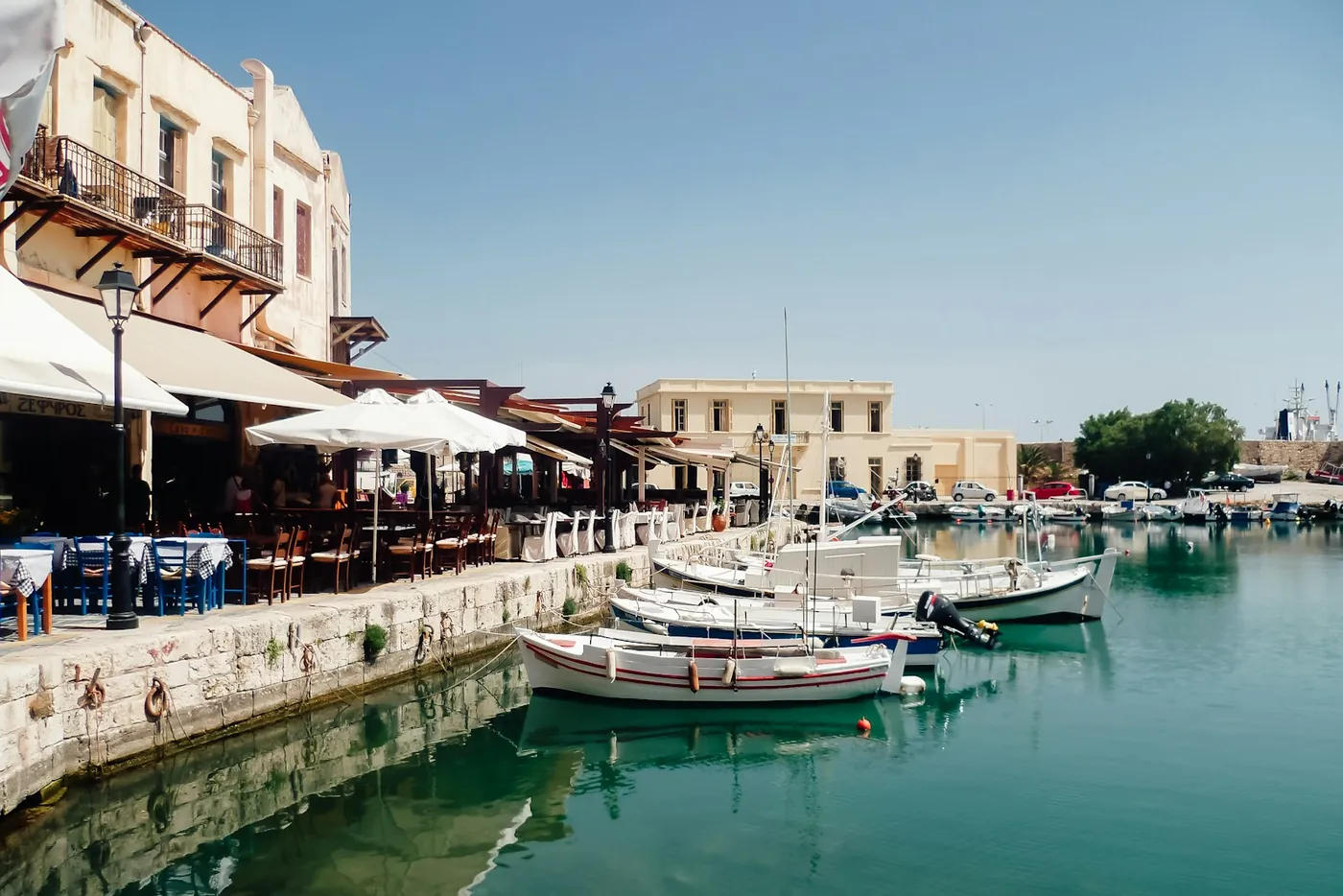 Fishing boats moored along a Venetian harbour front lined with tavernas and awnings, Crete, Greece