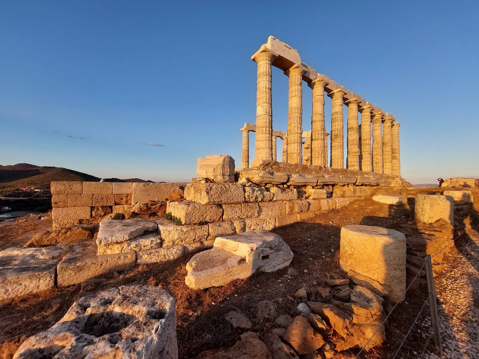 Temple of Poseidon at Cape Sounion, Greece, glowing at sunset above the sea