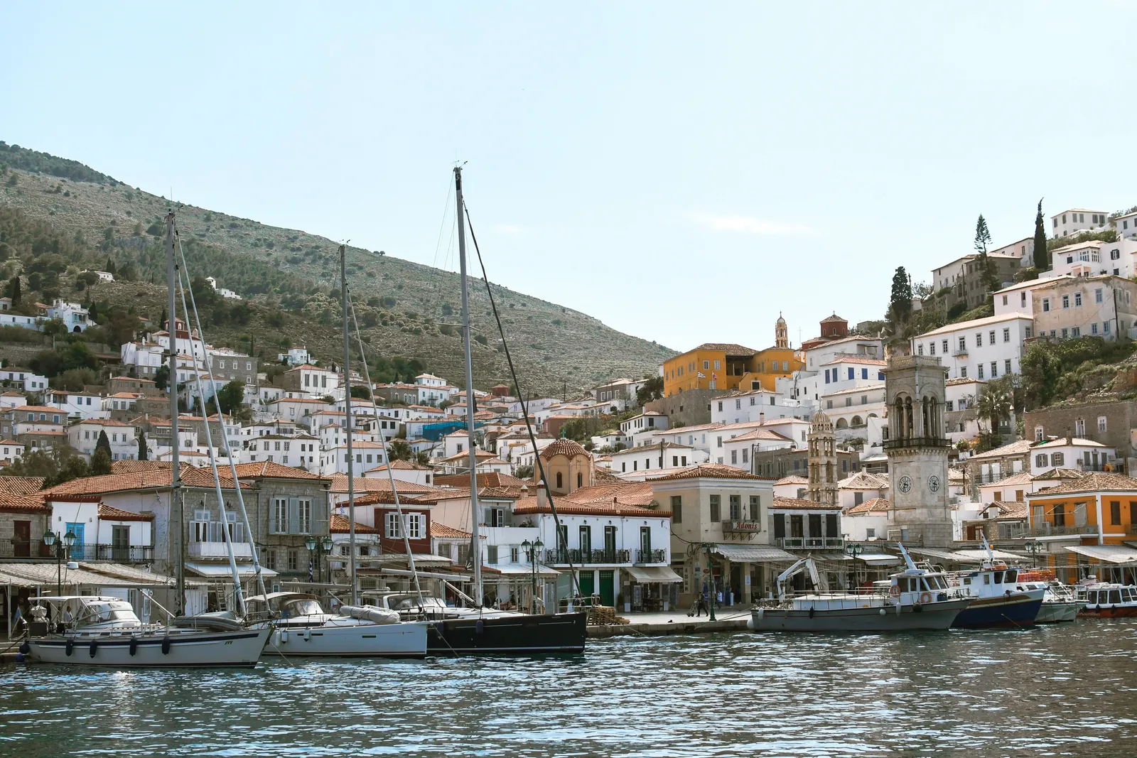 Hydra harbour with stone mansions rising up the hillside and fishing boats moored below, Saronic Gulf, Greece