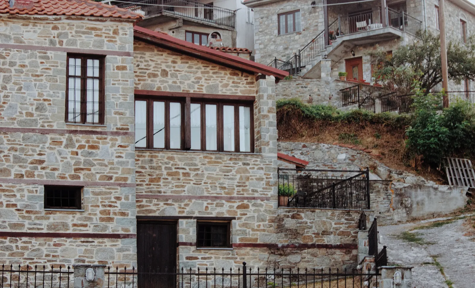 A stone built village house with wooden framed windows and balconies on a mountain slope