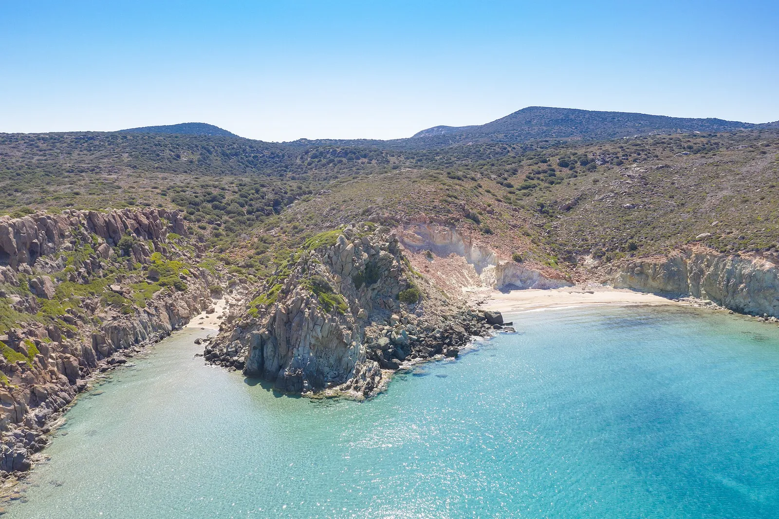 A sheltered bay with pale cliffs and clear shallow water on Milos, Greece
