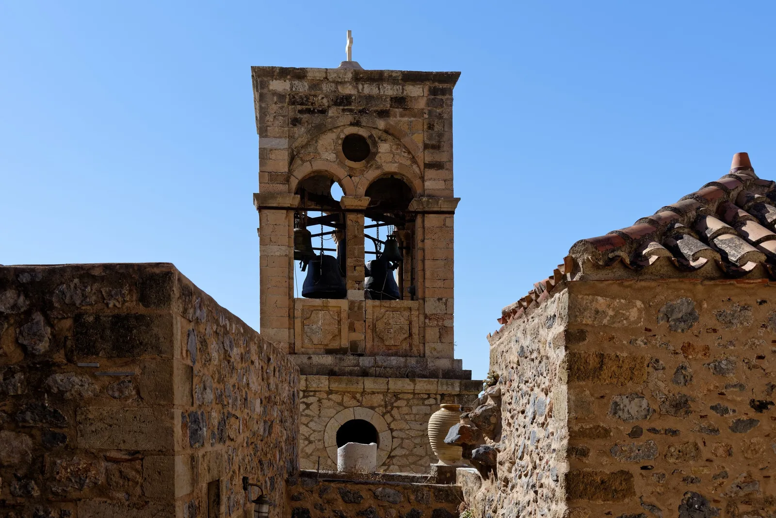 A stone bell tower and old houses inside a walled Byzantine town in Greece