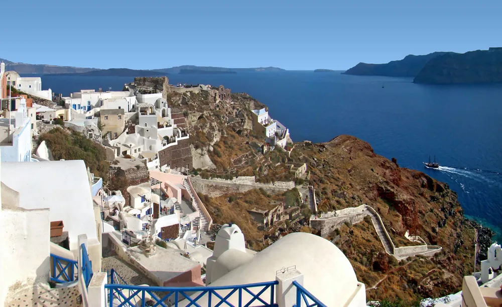 Whitewashed houses and blue domes stacked on the caldera cliffs of Oia, Santorini, high above the Aegean sea