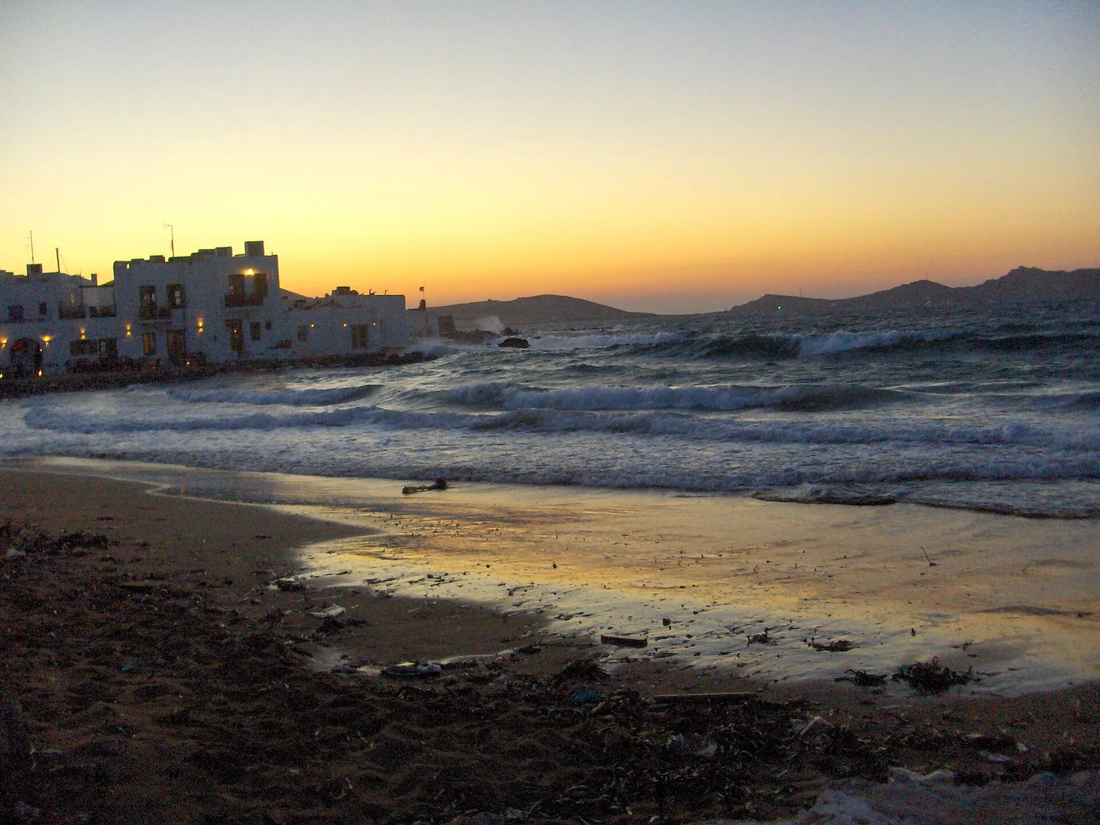 The sun setting over the sea beyond a Cycladic town on Paros, Greece