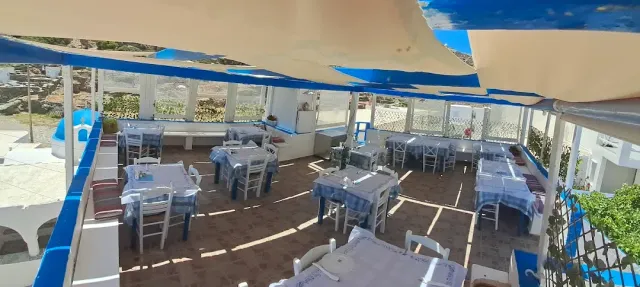 A terrace covered with shade sails, with tables in blue and white checked cloths