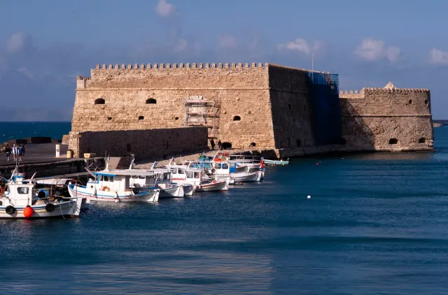 A Venetian stone fortress on a breakwater with boats moored in front of it