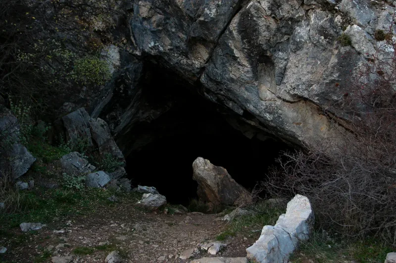 The mouth of the Corycian Cave on the slopes of Parnassus, framed by limestone boulders