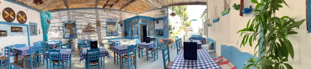 A terrace with blue and white checked cloths, blue wooden chairs and wall decorations