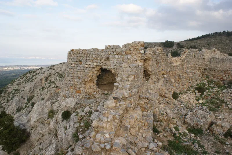 Crumbling stone walls of Palaio Pyli castle on a scrub covered hill in Kos