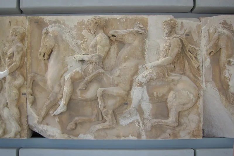 An ancient marble relief of riders and horses displayed on the museum wall