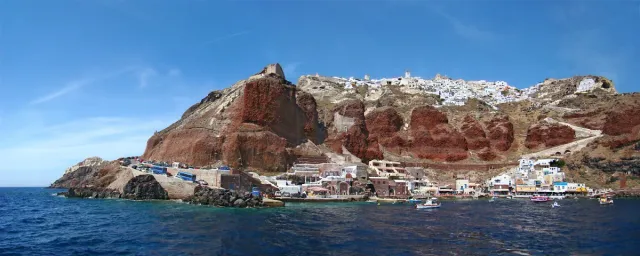 A small fishing harbour at the foot of reddish cliffs dropping into the sea