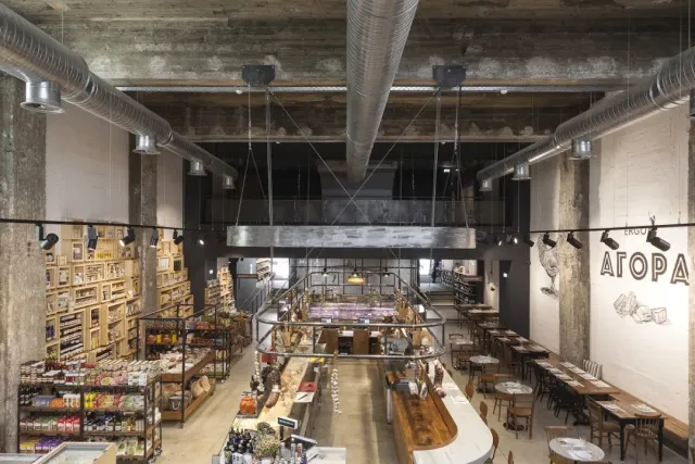 A tall industrial hall with product shelves, counters and seating tables in the middle