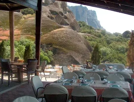 Tables set under a canopy, facing hills and towering rock pillars