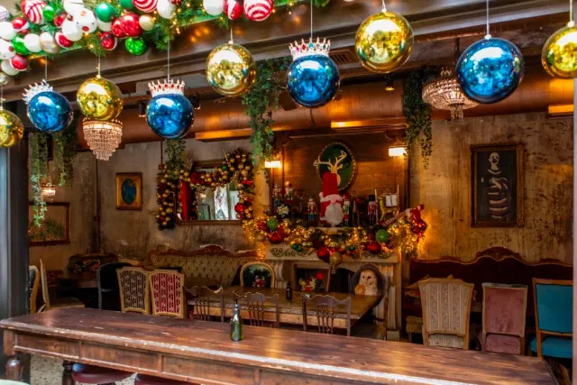 A space with hanging decorative baubles, chandeliers, an antique sofa and a long wooden counter