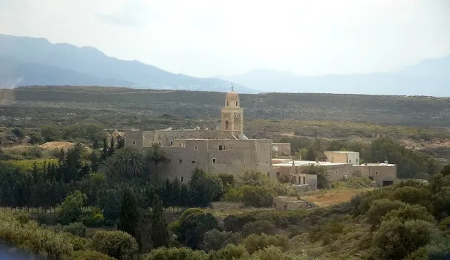 A fortified monastery with a tall bell tower standing alone in dry hill country