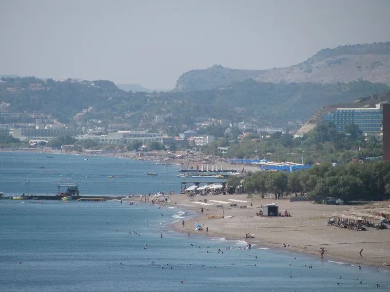 Faliraki beach on Rhodes, a wide strip of sand with bathers and hotels behind