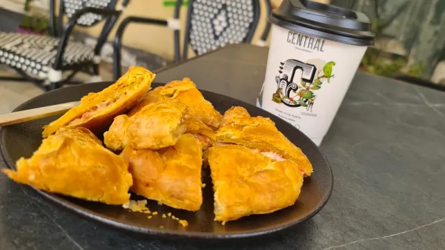 A plate with pieces of golden puff pastry, and a coffee cup beside it