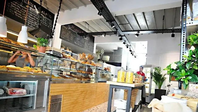 A bakery counter with loaves of bread, display cases and chalk menu boards above