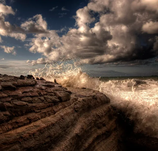 Steep sandstone cliffs above the sea in evening light, under heavy clouds