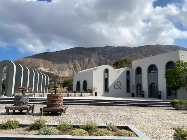 White buildings with arches, old wooden wine presses in the courtyard and a bare mountain behind