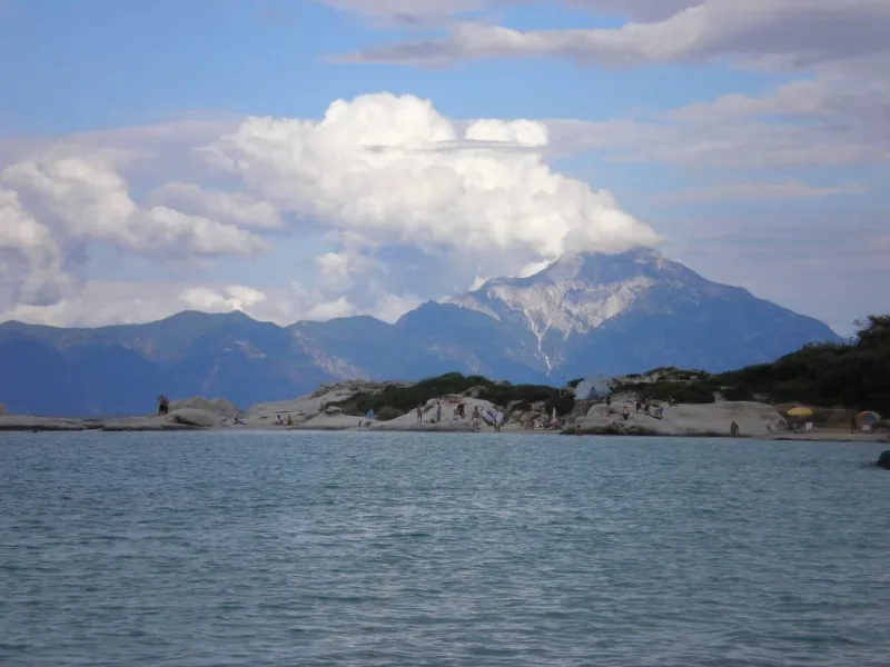 White rocks and bathers at Kavourotripes beach in Halkidiki, with snow capped Mount Athos across the water