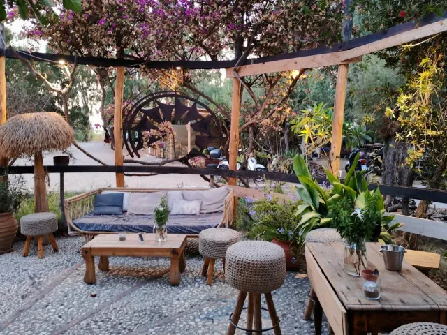 A garden seating corner under a pergola, a wooden sofa with cushions and knitted stools