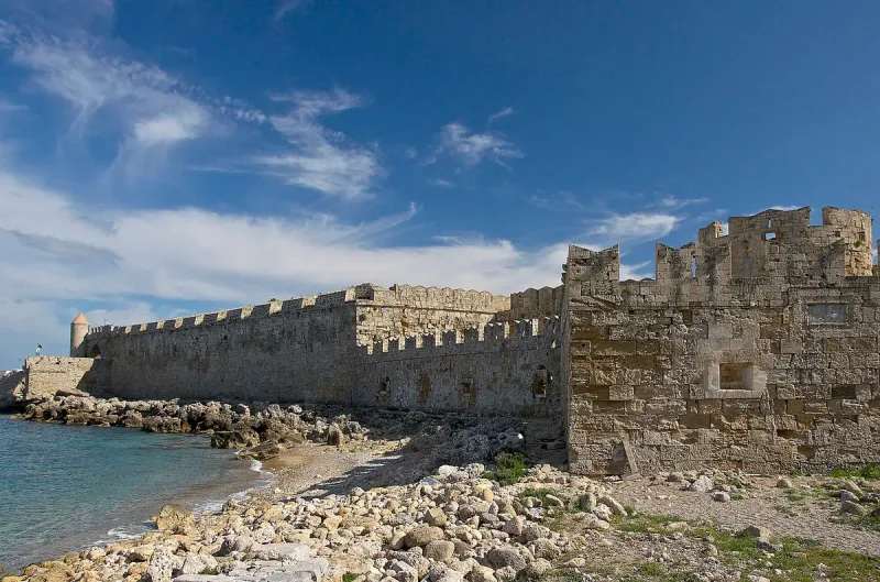 Massive fortress walls above a dry, grassy moat