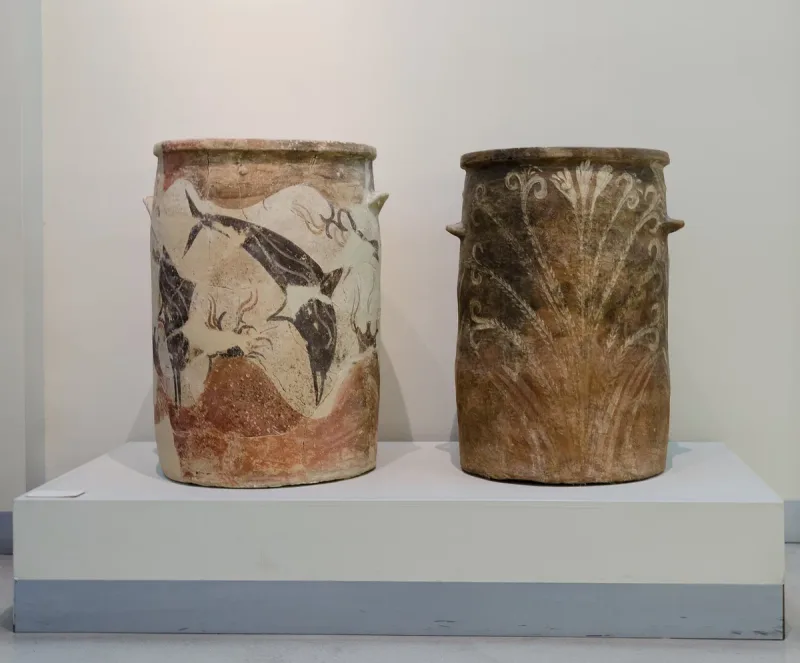 Two Minoan clay jars painted with dolphins and plants on a display plinth