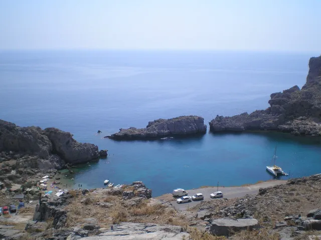An almost fully enclosed bay of clear blue water, ringed by rocky hills