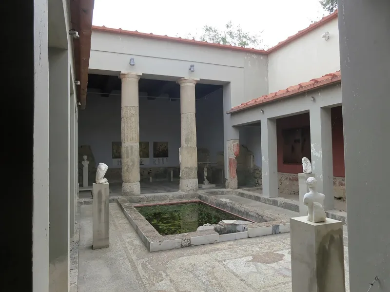 A colonnaded inner courtyard with a water basin and statues at Casa Romana, a restored Roman house in Kos town