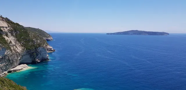 Deep blue sea seen from a clifftop, pale cliffs on one side and an island on the horizon