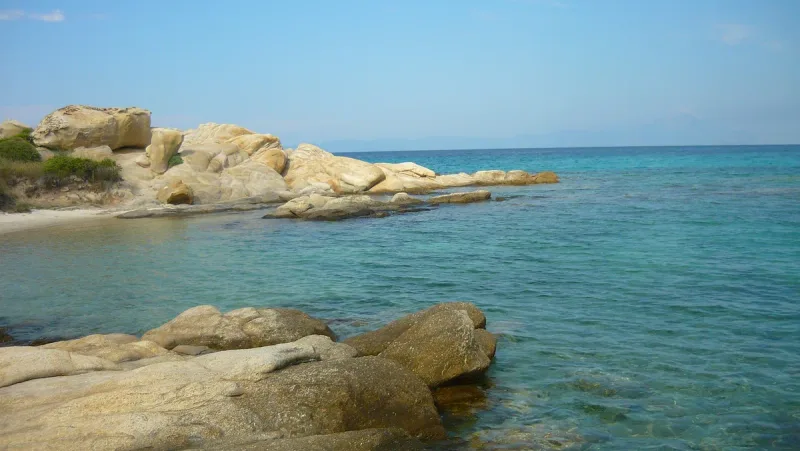 Smooth golden rocks running into clear turquoise water