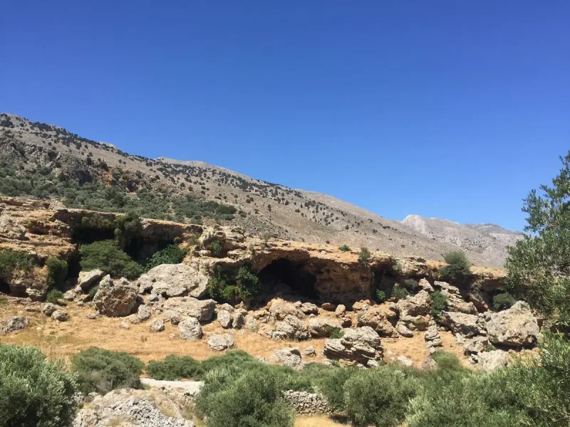A limestone slope with a cave hollow and bare cliffs at the Imbros gorge area in Crete, among olive trees