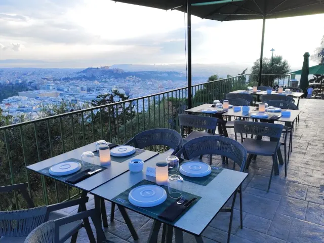 Tables set with light blue plates on a terrace, facing the city and a hill with a temple