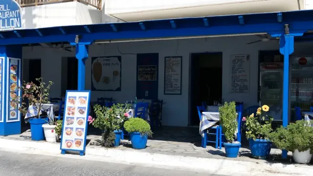 A blue and white frontage with photo menu boards, blue chairs and pots on the pavement