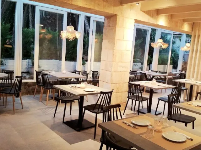 A modern dining room with stone pillars, black chairs and hanging straw lamps