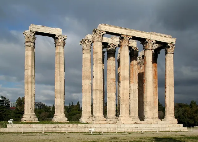 A row of tall Corinthian marble columns left from a temple, against the sky