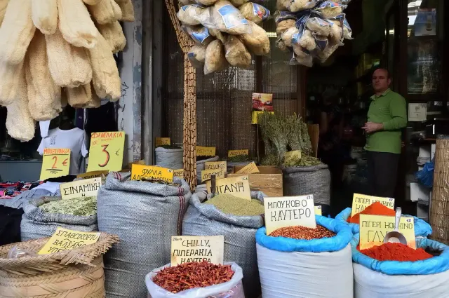 A covered market stall with sacks of colourful spices and price labels
