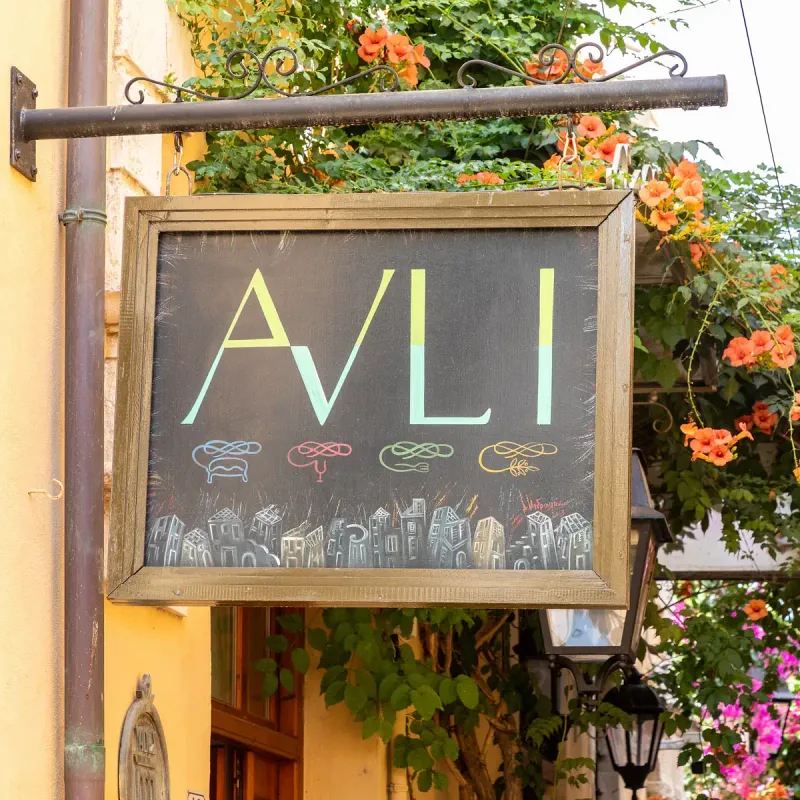 The sign of the Avli taverna in the old town of Rethymno, among climbing flowers
