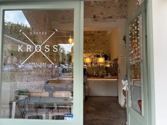 An open glass door onto a stone space with a lit counter and strings of lights
