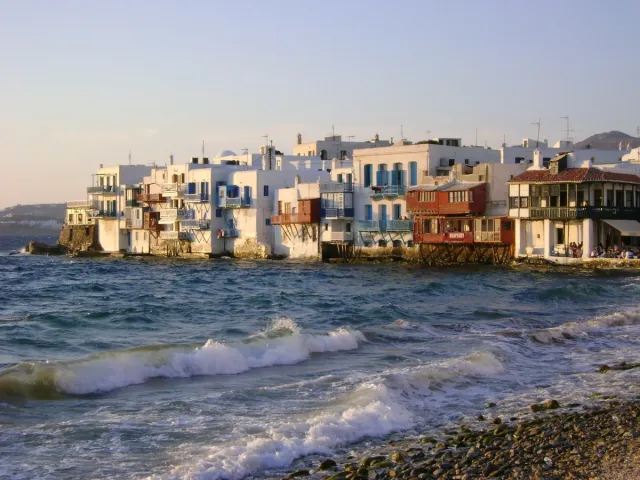 Colourful houses with wooden balconies built at the waterline, waves breaking below