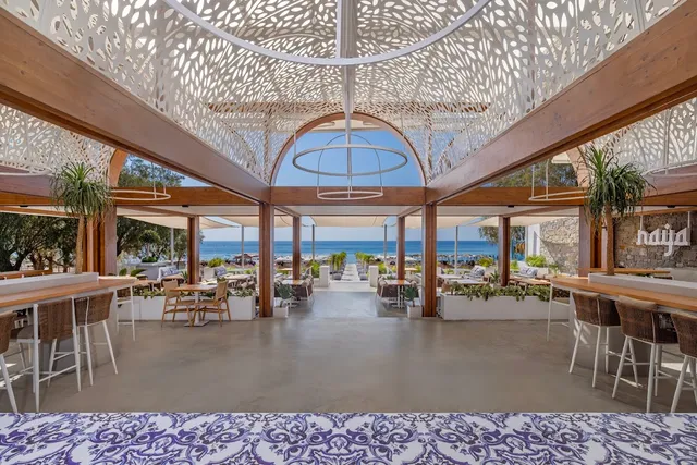 An open hall with a lace patterned perforated roof and bar counters, facing the sea