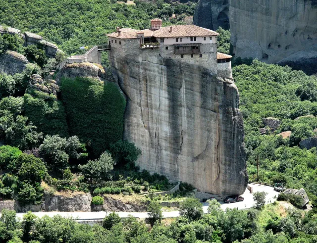 A monastery built on top of a rock pillar, surrounded by green forest